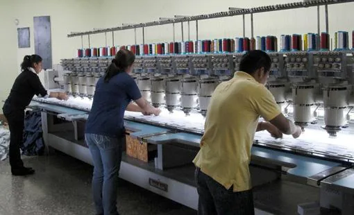Operarios trabajando en la máquina de bordado computarizado de varios cabezales de Uniformes OR