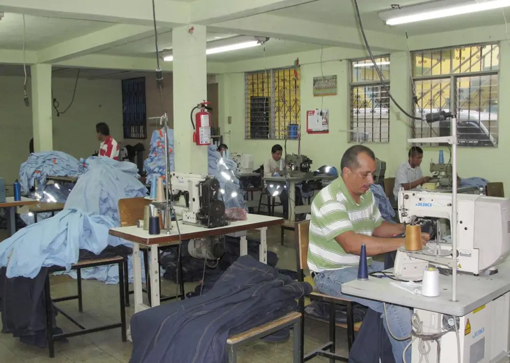 Operarios cosiendo uniformes en el taller de Uniformes Industriales OR en San Juan Opico